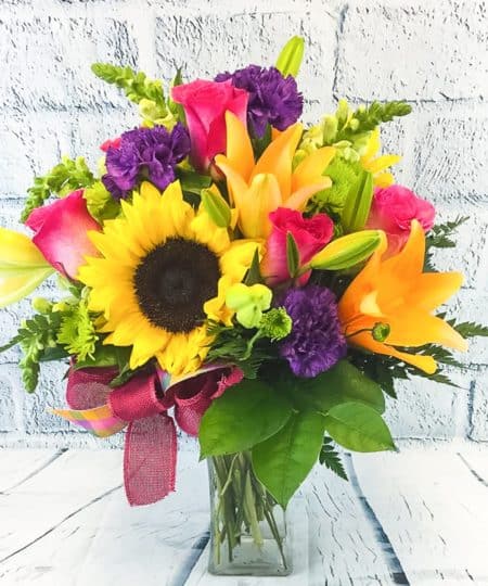 The name says it all. Send your Happy Heart with these eye-catching Sunflowers, Asiatic Lilies, and Roses are a great place to start. We combine the brilliant colors and textures by adding Snapdragons and daisy poms, perfectly placed, to create a bold burst of a flower bomb! We love this arrangement for its vibrancy of colors and soft floral scents. Perfect for a celebration or to add cheer for those that need encouragement.