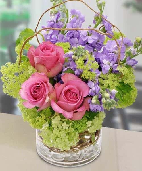 Put a smile on her face with a bouquet featuring roses, hydrangea and stock flower are arranged in a glass cylinder vase, accented with curly willow tips and clear gem stones.