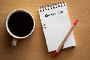 Bucket list, red pen, coffee mug